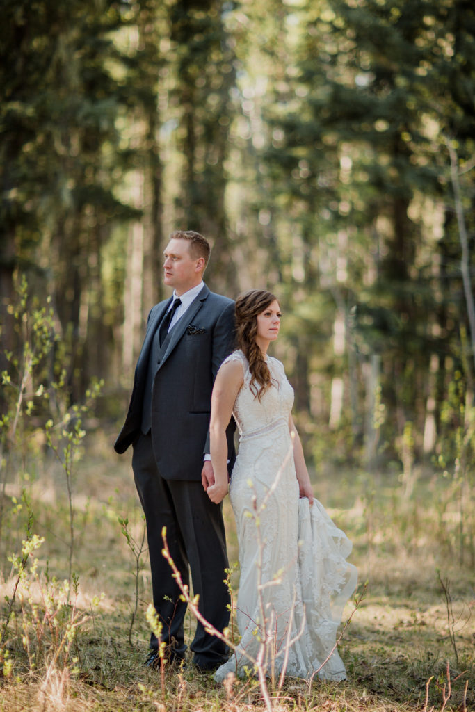 couple standing in the woods with their backs to each other.